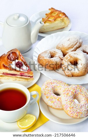 still life of setout table with baking pies, donuts, tee cup and pot. Image with white background. Russian cuisine