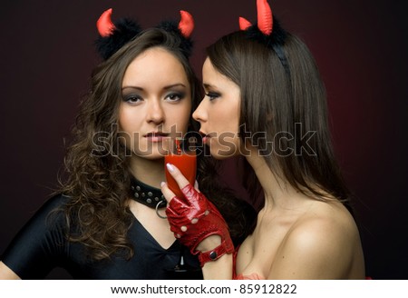 Two beautiful women in devil carnival shapes.