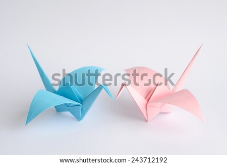 Blue and pink origami birds kissing each other