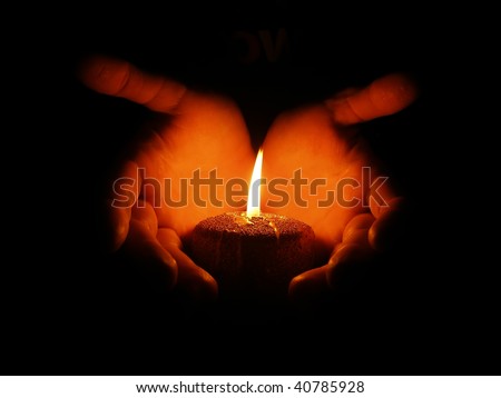 Hands round a burning candle on a black background (look at my candles photo)