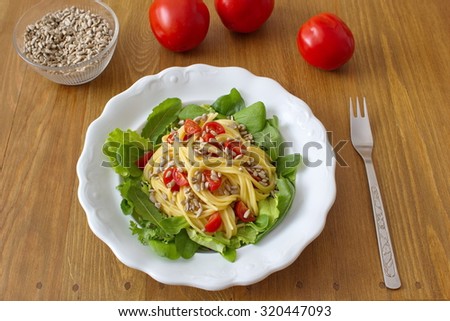 healthy dinner consists of salad and pasta with tomatoes and sunflower seeds