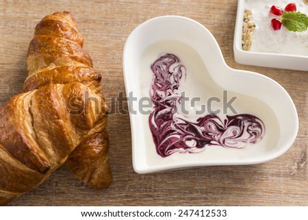 healthy and fresh breakfast with bowl of fruit yogurt and croissant on the brown table.