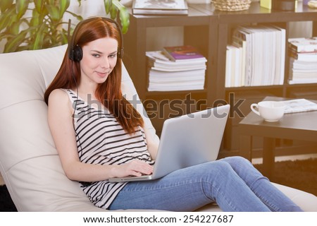 Woman listening to music on the laptop in the room.