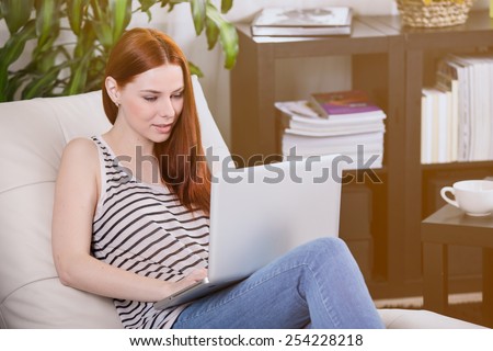 Woman read the notebook on the sofa in the room.