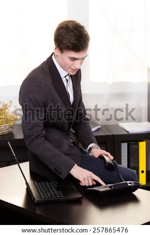 Business man sitting on a table and call someone in the office