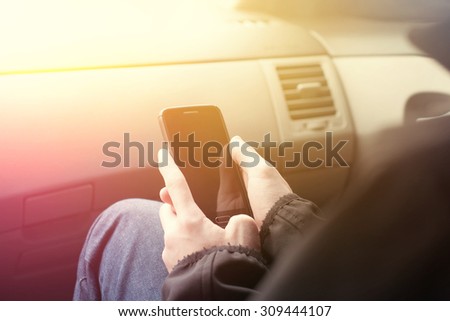 Young man using phone sitting in the car
