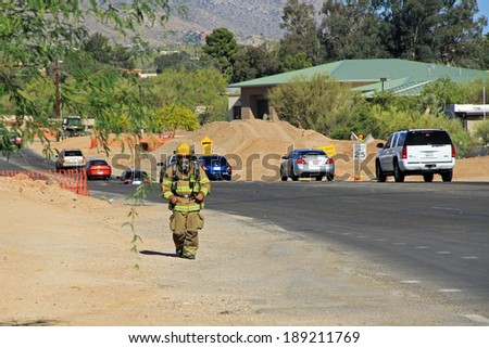 TUCSON, ARIZONA, USA --April 21, 2014:  A Firefighter who is training by running alongside the road with his protective suit and air pack on.