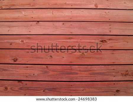 Wooden slats on a weathered wooden deck with redwood stain.