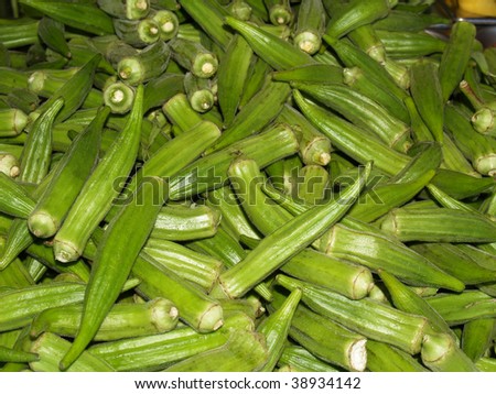 Large pile of fresh green okra pods in a farmers market.