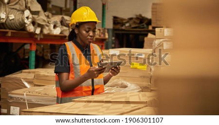Young African female warehouse worker working on a digital table during an iventory check Сток-фото © 