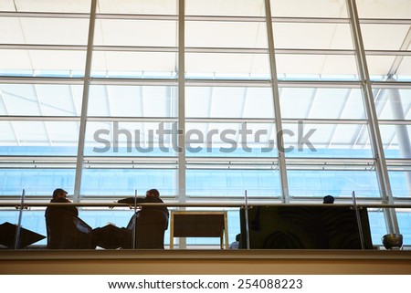 Interior shot of businesspeople silhouetted against high rise windows inside a modern building
