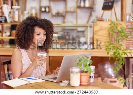 Beautiful young freelancer working on her laptop in a coffee with wifi
