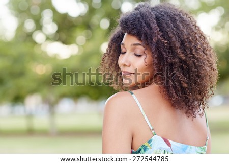 Beautiful woman with curly hair looking relaxed with her eyes closed in a natural setting
