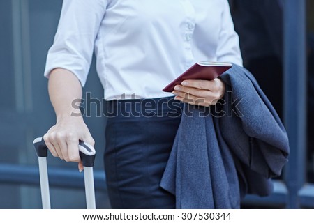 Cropped shot of a businesswoman with luggage and her passport