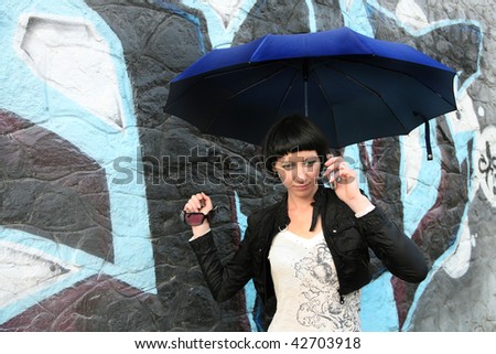 Girl speaking to someone on the sell phone under umbrella