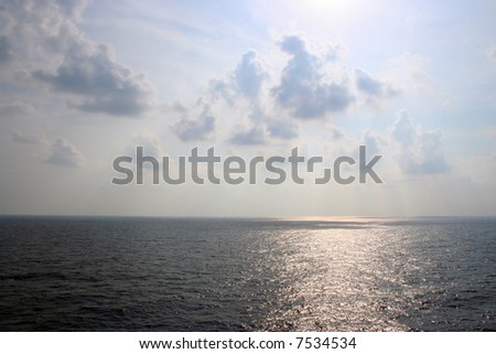 An ocean landscape with the sun shining down.