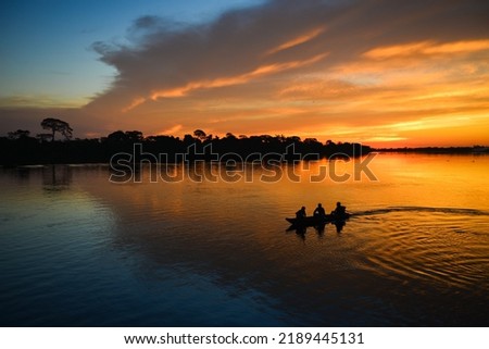 The silhouette of a small motorized canoe on the Guaporé - Itenez river at dusk, Ricardo Franco village, Vale do Guaporé Indigenous Land, Rondonia, Brazil, on the border with Bolivia Stockfoto © 