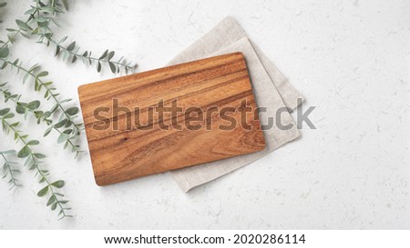 Wood cutting board with linen napkin and plant on marble table with copy space, top view Stok fotoğraf © 