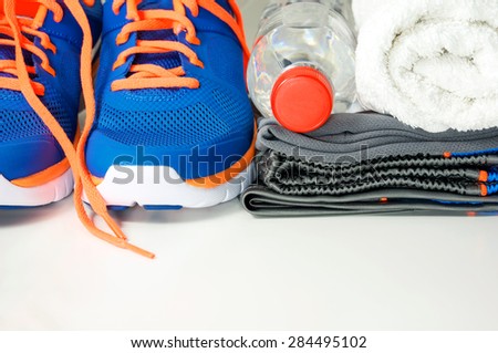 Fitness accessories with running shoes, sport clothing, drinking water and towel