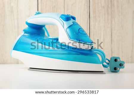Steam iron on white table with wood wall background