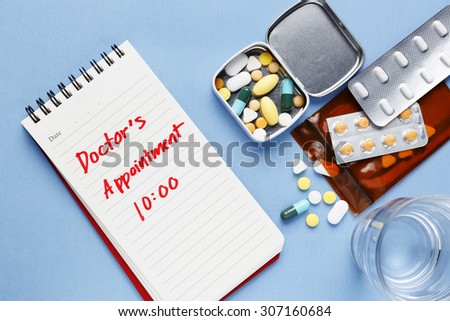Doctor appointment note with pills on table