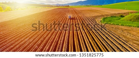 Farmer in tractor preparing land with seedbed cultivator in farmlands. Tractor plows a field. Agricultural work in processing, cultivation of land. Furrows row patter. aerial photo 商業照片 © 