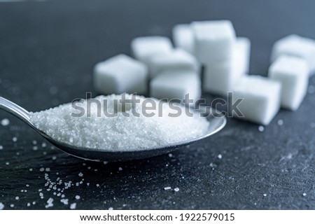 sugar cubes on black backround. Sugar is unhealthy nutrition and leads to obesity, diabetes, dental care
