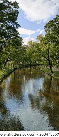 Similar – Foto Bild Kleiner Fluss in einem lettischen Wald, aufgenommen von einer Brücke. Das Wasser ist mit Wasserpflanzen bewachsen, viele Grüntöne und einige Gelbtöne. Frühherbst Landschaft, bewölkten grauen Himmel