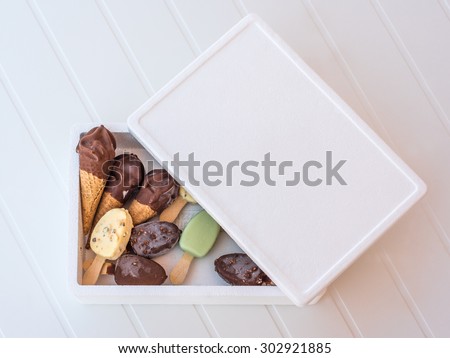 A box full of ice cream of different shapes with a cover half-opened on a white striped background
