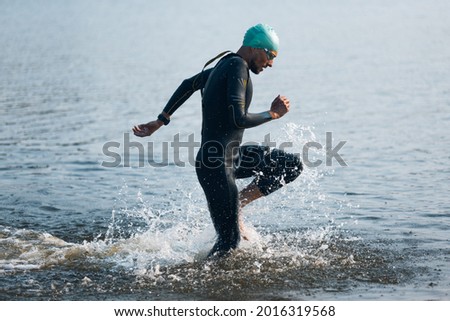 Professional triathlete swimming in river's open water. Man wearing swim equipment practicing triathlon on the beach in summer's day. Concept of healthy lifestyle, sport, action, motion and movement. Imagine de stoc © 