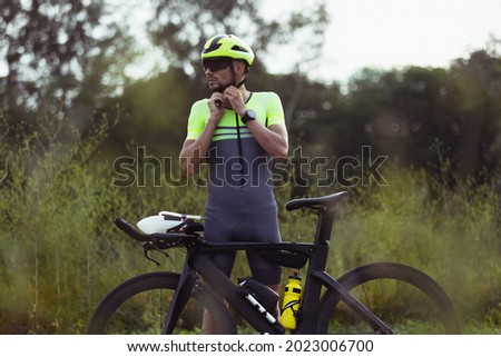 Taking a rest. Professional triathlete riding a bike on the open road. Professional sportsman is engaged in triathlon on bright summer day. Concept of healthy lifestyle, sport, motion, activity. Foto stock © 