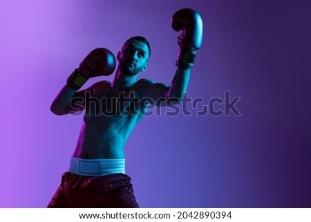 Uppercut. One professional boxer in gloves training, exercising on purple neon background. Fighter practicing in action. In motion. Health, sport, motion concept. Copy space for ad. ストックフォト © 