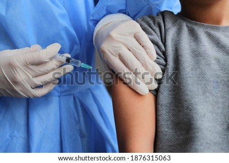 Little boy getting vaccinated from Covid-19. A young doctot's hand holding a  vaccine syringe.