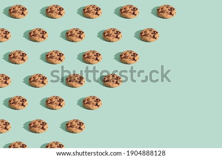 Trendy pattern made  of chocolate chip cookies on bright green mint background. Minimal concept, diagonal copy space.