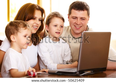 happy family using laptop; shallow DOF, focus on elder boy\'s eyes
