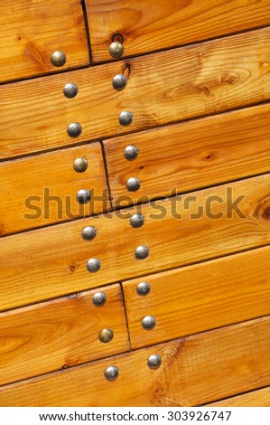 Detail of a lacquered wood surface of a boat with nails for background
