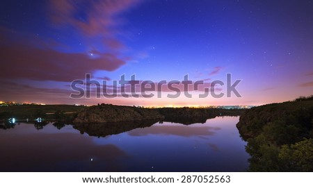 Beautiful night sky at the river with stars, clouds and reflections in the water. Summer in Ukraine