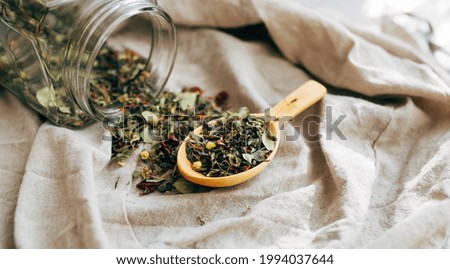 herbal tea. dried herbs. dried various herbs in a wooden spoon next to a glass jar with rashes of herbs on a light background