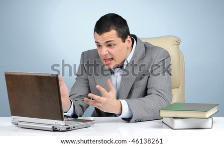 Angry businessman at work on gray background