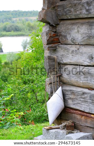 Old wooden cottage with fishing buoy and river in background.