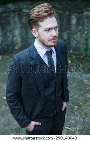 Elegant young handsome man in classic costume in city park.Fashion portrait of young  man in classic costume.Business men in class costume
