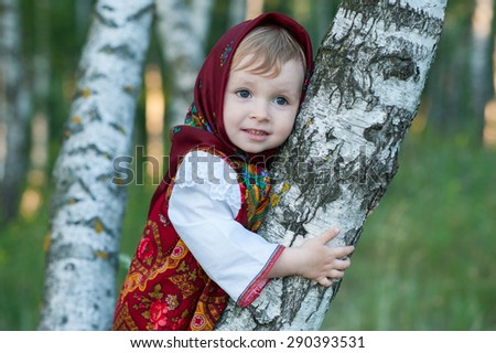 Beautiful little girl in russian traditional clothes in nature.Little cute girl in Russian national clothes.Traditional Russian folk costume.Portrait of a cute little girl outside