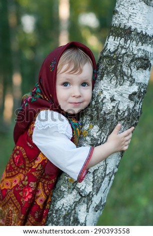 Beautiful little girl in russian traditional clothes in nature.Little cute girl in Russian national clothes.Traditional Russian folk costume.Portrait of a cute little girl outside