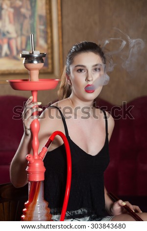 Beautiful woman smoking hookah in bar.The beautiful sensual woman with a hookah