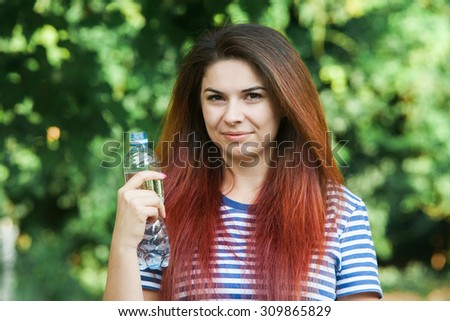 Portrait of young smiling woman with bottle of water, outdoor.A close up portrait of a young woman with bottle of water