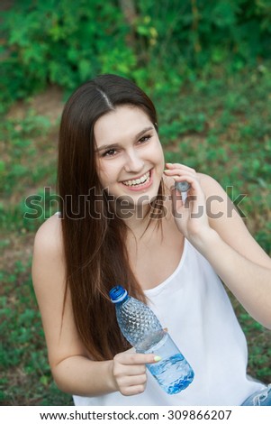 Portrait of young smiling woman with bottle of water, outdoor.A close up portrait of a young woman with bottle of water