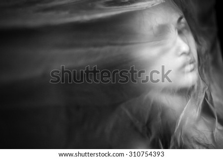 woman under transparent textile.woman under dark textile.mysterious woman blurred. Mysterious portrait of a girl in the dark, in the fog