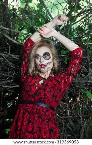 Halloween makeup. Fashion photo of gothic girl in Halloween dress in a forest. Devils costume and makeup.
