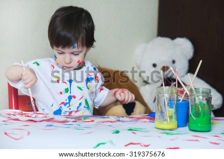 Cute little boy painting with brush. Cute little boy painting and splatter with colors creativity on table.