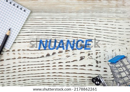 NUANCE - word (text), on a white wooden table, a notebook and a trolley, a grocery basket. Business concept: buying, selling, commerce (copy space). Imagine de stoc © 